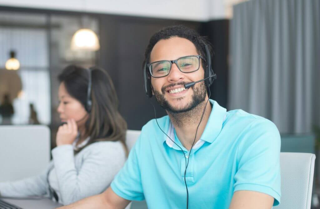 Smiling call center agent wearing headset and glasses.
