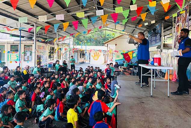 Children watch a science demonstration under colorful flags at an event.