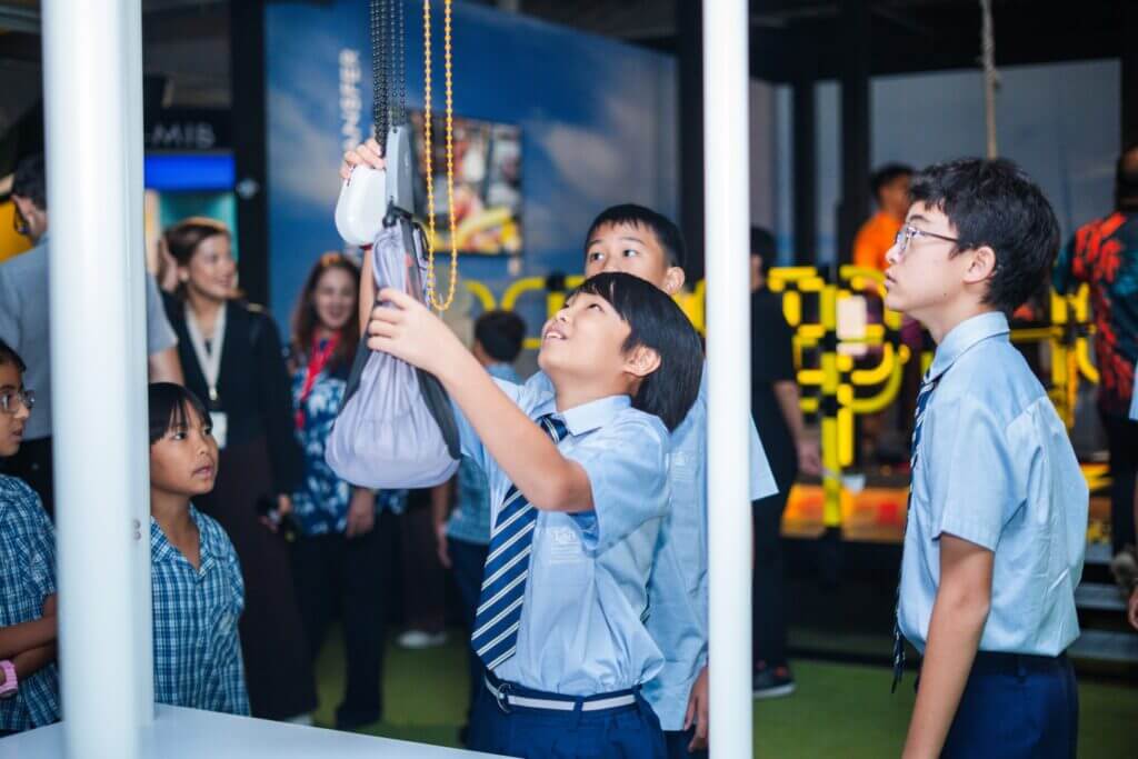 Students in school uniforms interact with an interactive display.