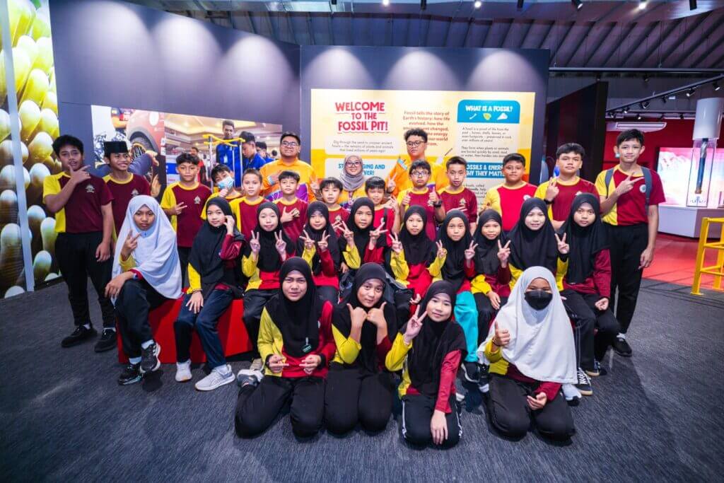A group of students pose at the "Welcome to the Fossil Pit!" exhibit.